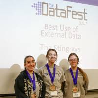 Three students awarded the Best Use of External Data Award pose in front of the DataFest logo.